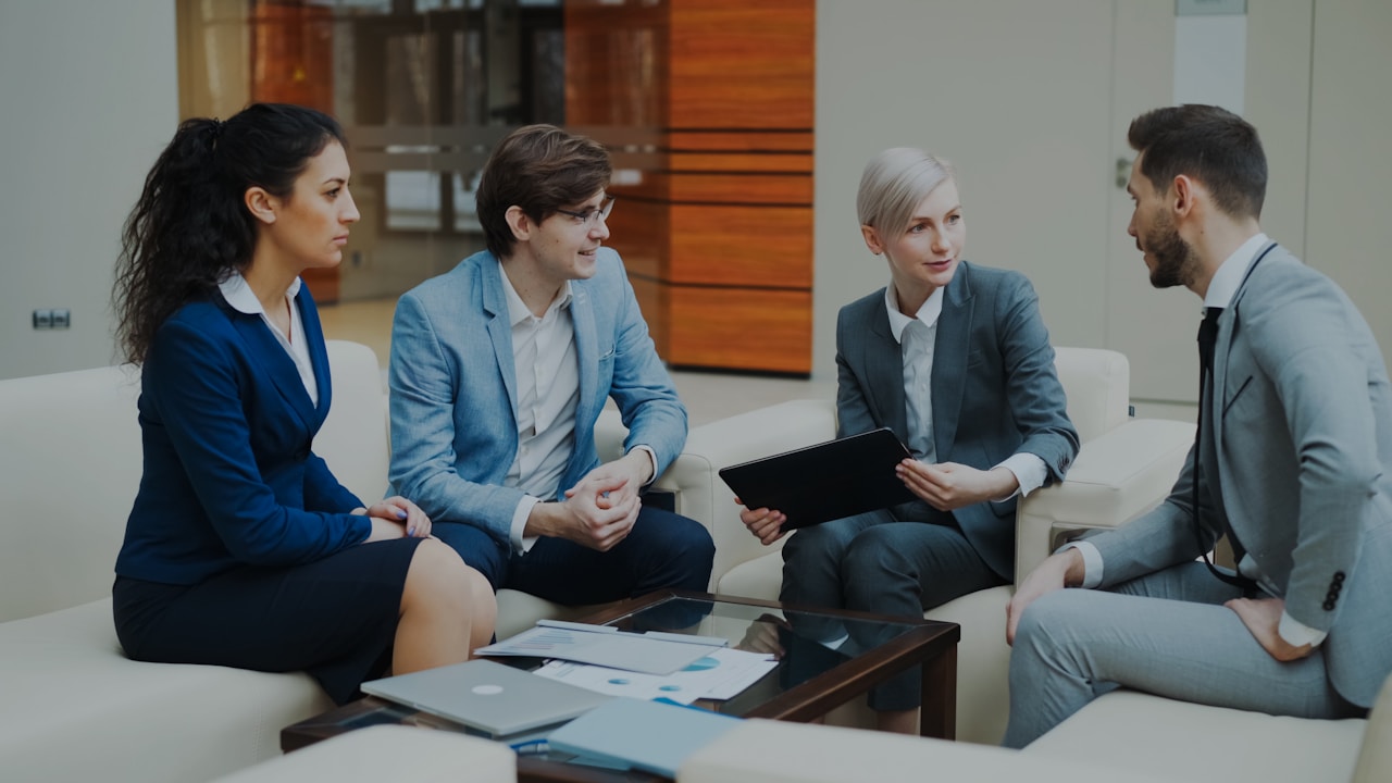 Meeting between four businesspeople on white sofas